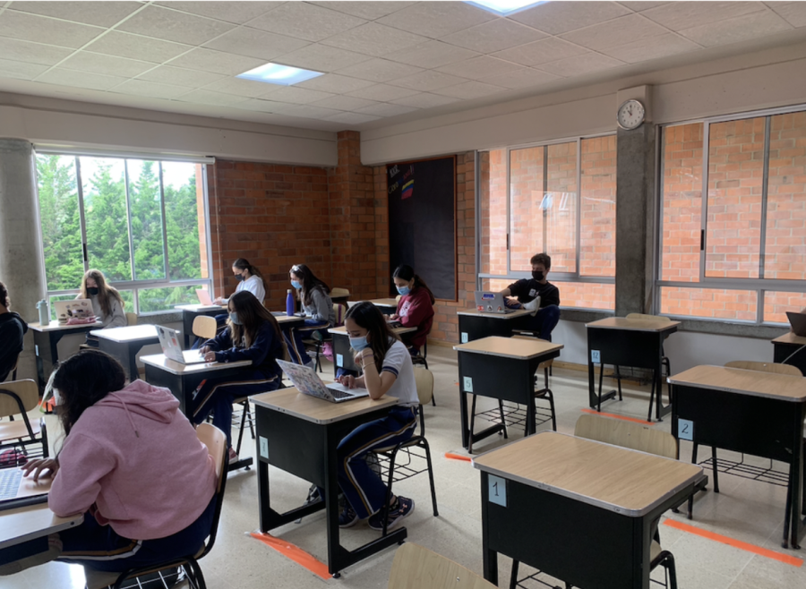 10th-grade students work individually on their sociales projects. This image clearly shows how students follow the protocols by maintaining social distancing and having a mask on.
