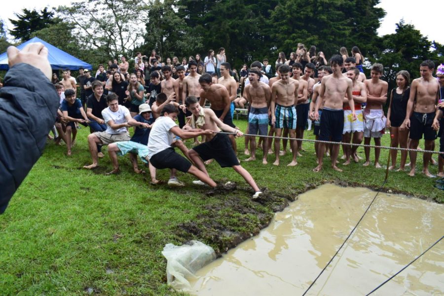 Highschool students play tug of war trying to drag the other team into the water. 