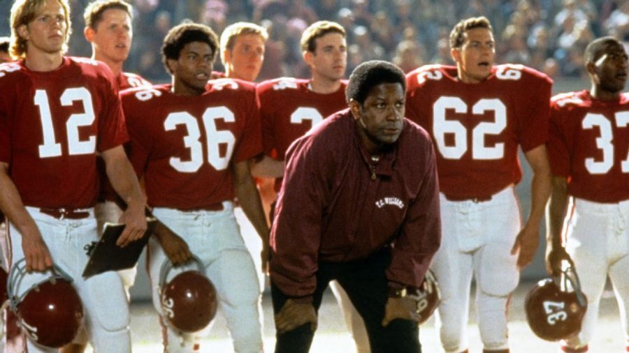 Coach Boone (portrayed by Denzel Washington) looking on from the sidelines along with his team behind him during a regular season game.