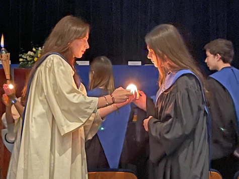 M.Mesa, NHS Treasurer, hands the candle to J.Wolff, a new member.  The candles brightness symbolizes each members courage in regards to the community, institution, and neighborhood.