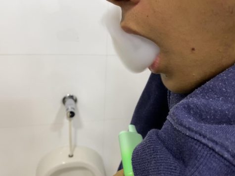 A student vapes in a bathroom.