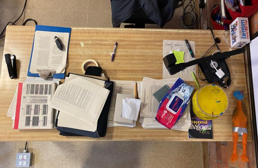 David Gold, English HS teacher’s desk resembles the way his brain works. Gold constantly writes things down on his board, otherwise, he will forget, he always thinks about the next activity, lesson, essay, or project. His desk is in front of the door and holds different types of essays, rubrics, books, energizer activities, and even a chicken. 