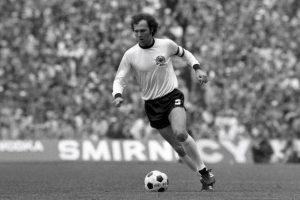 Franz Beckenbauer sprints with a ball in his feet during an international game with Germany.
